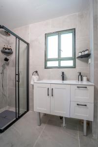 a white bathroom with a sink and a shower at בצל הדקל in Bet Leẖem HaGelilit +28 photos