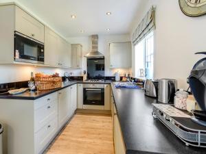 a kitchen with white cabinets and black counter tops at The Bay - The Bolthole in Reighton +17 photos