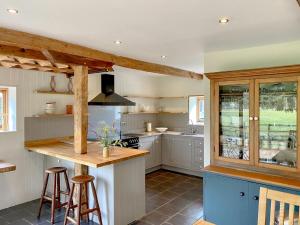 a kitchen with white cabinets and a counter with stools at The Granary in Oxborough