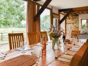 a long wooden table with glasses and a vase of flowers at The Granary in Oxborough