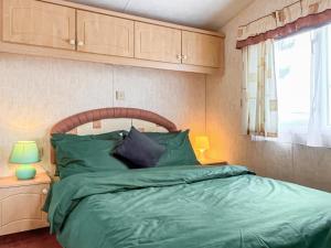 a bedroom with a bed with green sheets and a window at Oakmere - Uk51989 in Oakmere