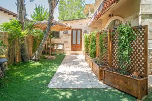 a garden with a wooden gate and a house at בצל הדקל in Bet Leẖem HaGelilit