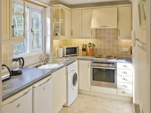 a kitchen with white cabinets and a sink at River Lodge in Polperro