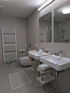 a bathroom with two sinks and a toilet and a mirror at Apartment VIEW 27 in Olomouc