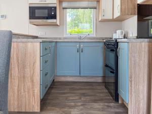 a kitchen with blue cabinets and a window at Whispering Pines Spa - Uk50087 in Durham