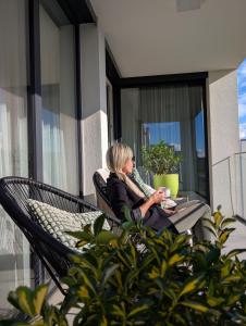 a woman sitting in a chair on a balcony at Apartment VIEW 27 in Olomouc