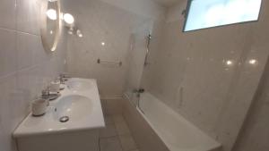 a white bathroom with a sink and a bath tub at la Villa des Fleurs in La Bourboule +24 photos