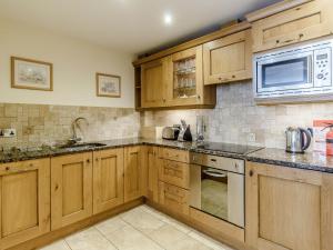 a kitchen with wooden cabinets and a microwave at Orchard Sands in Beadnell