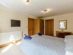 a bedroom with a large white bed and a television at Orchard Sands in Beadnell +4 photos