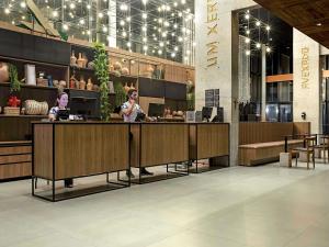two people standing at a counter in a lobby at ibis Styles Maceió Pajuçara in Maceió