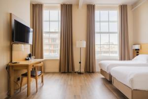 a hotel room with a bed and a desk with a television at School Lane Hotel in Liverpool ONE in Liverpool
