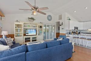 a living room with blue couches and a tv at 1030 - La Ballena Cottage in Corolla