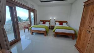 two beds in a white room with a window at Double view point sibetan in Tenganan
