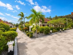 a courtyard with palm trees and houses at Bugbug Beach Resort in Gili Biaha