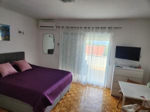 a bedroom with a purple bed and a window at Apartmani Kramar in Selce