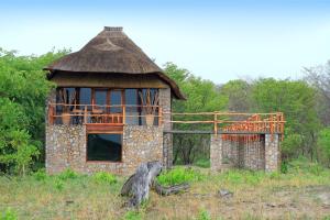 un antiguo edificio de piedra con techo de paja en un campo en Gwango Elephant Lodge en Dete
