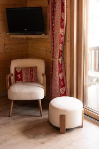 a chair and a ottoman in a room with a television at Chardonneret 3 in La Clusaz