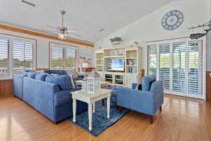 a living room with blue couches and a clock at 1030 - La Ballena Cottage in Corolla