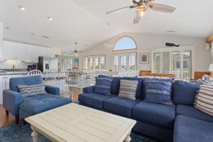 a living room with blue couches and a kitchen at 1030 - La Ballena Cottage in Corolla