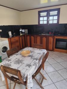 a kitchen with a table and chairs with a table and a table and a table at Studio Zen Attitude à 10 minutes des belles plages in Le Marin
