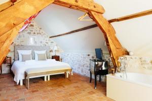 a bedroom with a bed and a tub in a attic at La Boire Bavard in Blaison +36 photos