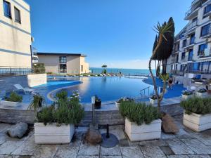 a resort with a swimming pool with a palm tree at Студио C19 в к-с Blue Bay Palace in Pomorie