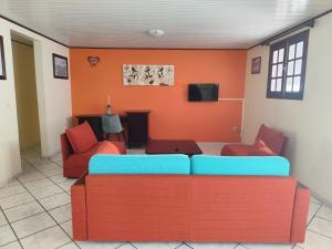 a living room with orange walls and a couch at Studio Zen Attitude à 10 minutes des belles plages in Le Marin