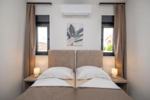 a bedroom with a bed with two windows at Holiday home Mirage in Sukošan