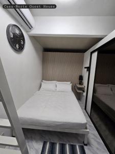 a bed in a room with a clock on the wall at Casa-Norte Guest House in San Jose
