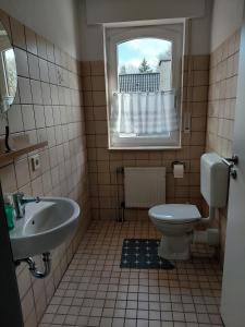 a bathroom with a sink and a toilet and a window at Ferienwohnung Knoll in Lähden