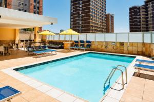 a pool on the roof of a building with chairs and tables at Oceanic Apartment - City and Stadium Views3 - Self-Catering in Durban +26 photos