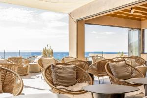 a patio with wicker chairs and tables and a view of the ocean at Kakkos Terra Blu Hotel in Ierapetra