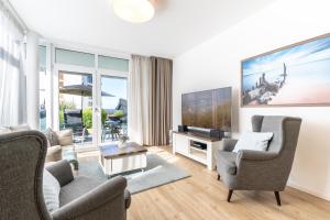 a living room with two chairs and a flat screen tv at Südkap C-02 in Pelzerhaken