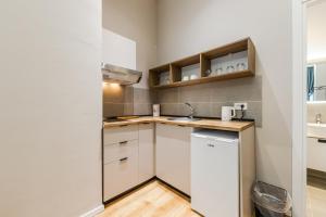 a small kitchen with white cabinets and a sink at Palm Beachfront Suites by PS in Durrës +117 photos