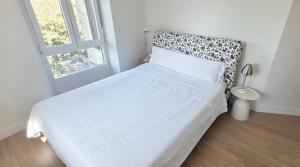a white bedroom with a bed and a window at Sand House Gorliz By Kima Gestión in Górliz-Elexalde