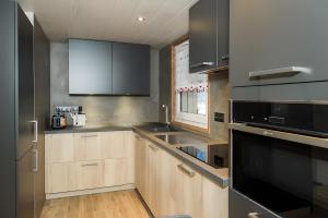 a kitchen with wooden cabinets and a black appliance at Gentiane 7 pers - proche pistes in Châtel