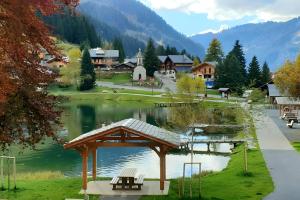 a lake with benches and a pavilion next to a town at Gentiane 7 pers - proche pistes in Châtel