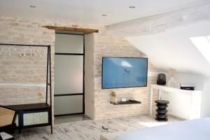 a bedroom with a tv on a brick wall at Plume Suites in Fleurey-sur-Ouche