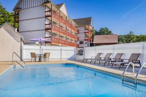 a pool with chairs and an umbrella next to a building at Days Inn by Wyndham Waynesville NC in Waynesville