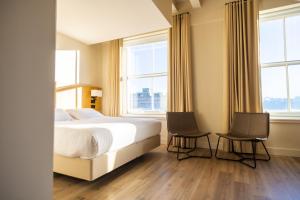 a bedroom with a bed and two chairs and windows at School Lane Hotel in Liverpool ONE in Liverpool