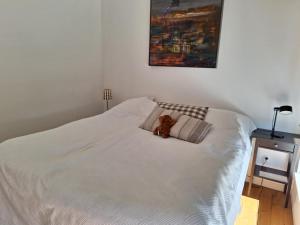 a teddy bear sitting on top of a white bed at Guesthouse in Gustavsberg