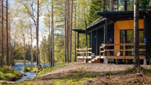 a man standing on the porch of a cabin in the woods at Aurakoski 1 in Ranua +16 photos