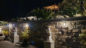 a stone wall with plants and a statue on it at VILLA PAPA PUTU in Banjar