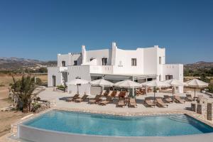 a large white building with a pool and chairs and umbrellas at Naxian Air in Naxos Chora