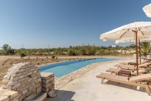 a swimming pool with benches and an umbrella at Naxian Air in Naxos Chora