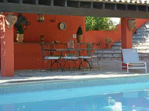 um pátio com uma mesa e cadeiras ao lado de uma piscina em Elegant house with swimming pool in H rault em Saint-Mathieu-de-Tréviers