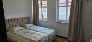 a small bed in a room with two windows at Turystyczna 9 apartamenty & cafe in Sobótka