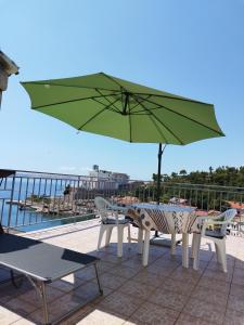 a table and chairs with a green umbrella on a roof at Apartman Jure in Jablanac