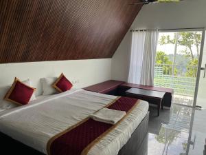 a bedroom with a bed and a desk and a window at Oxygen Rain Forest Resort in Kūmudi