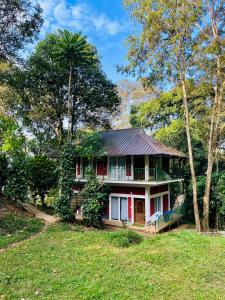 a house in the middle of a field with trees at Oxygen Rain Forest Resort in Kūmudi